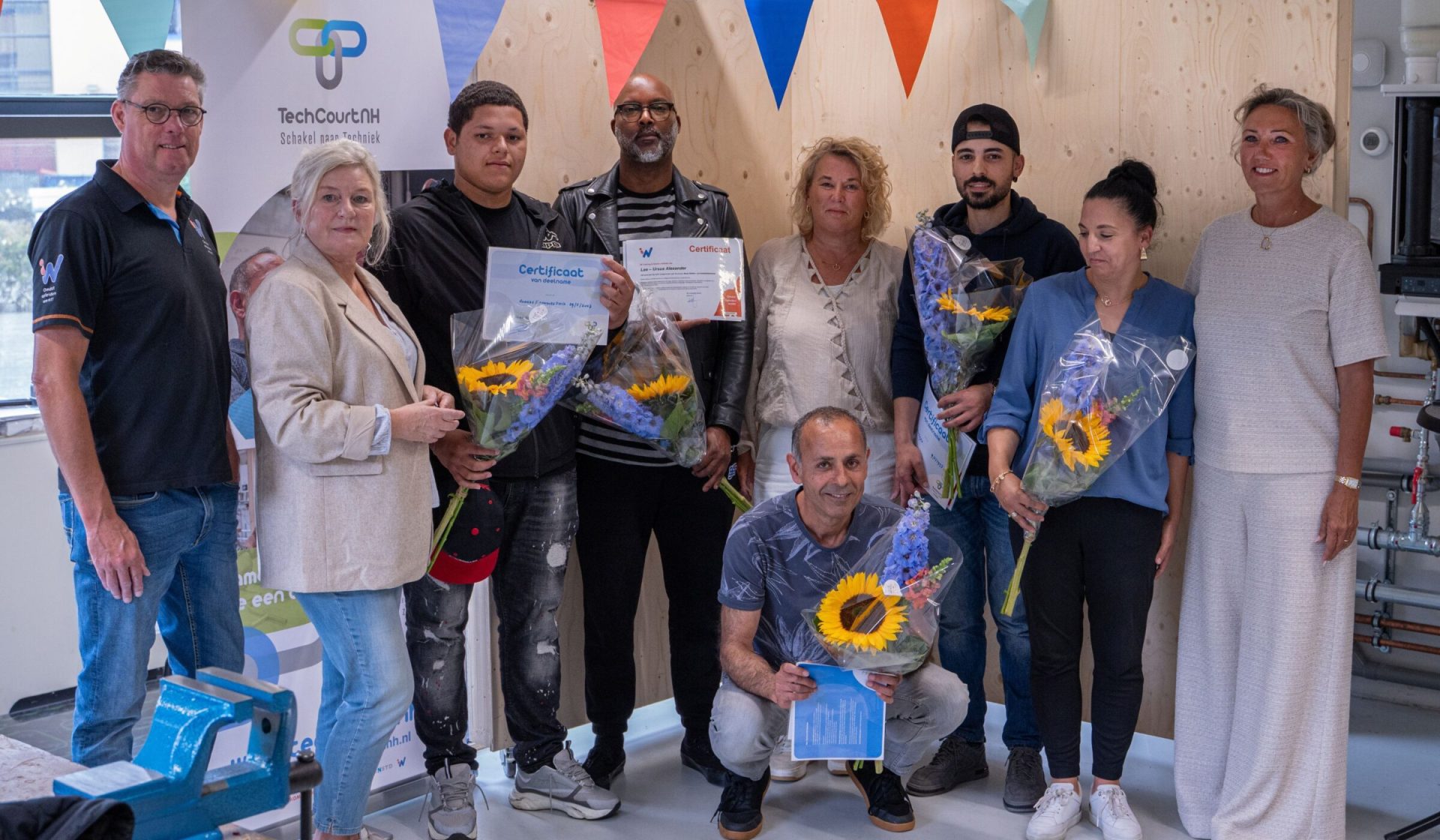 foto: Vijf kandidaten poserend met hun certificaat en bloemen.