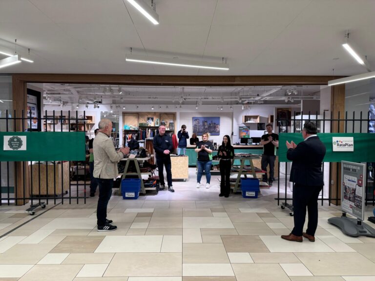 Rataplan: opening popupwinkel door wethouder Heggers. Meerdere medewerkers Rataplan applaudiserend in beeld.