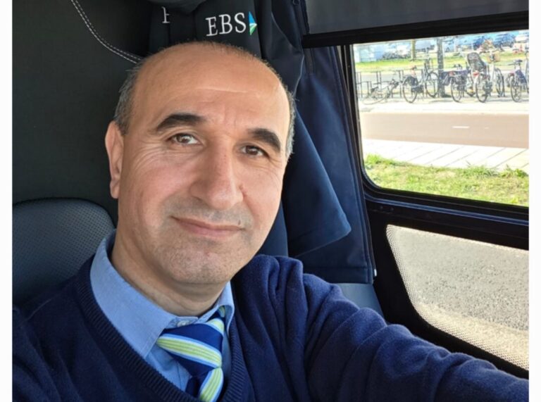 foto: buschauffeur Rebwar poserend achter het stuur in EBS-kleding.