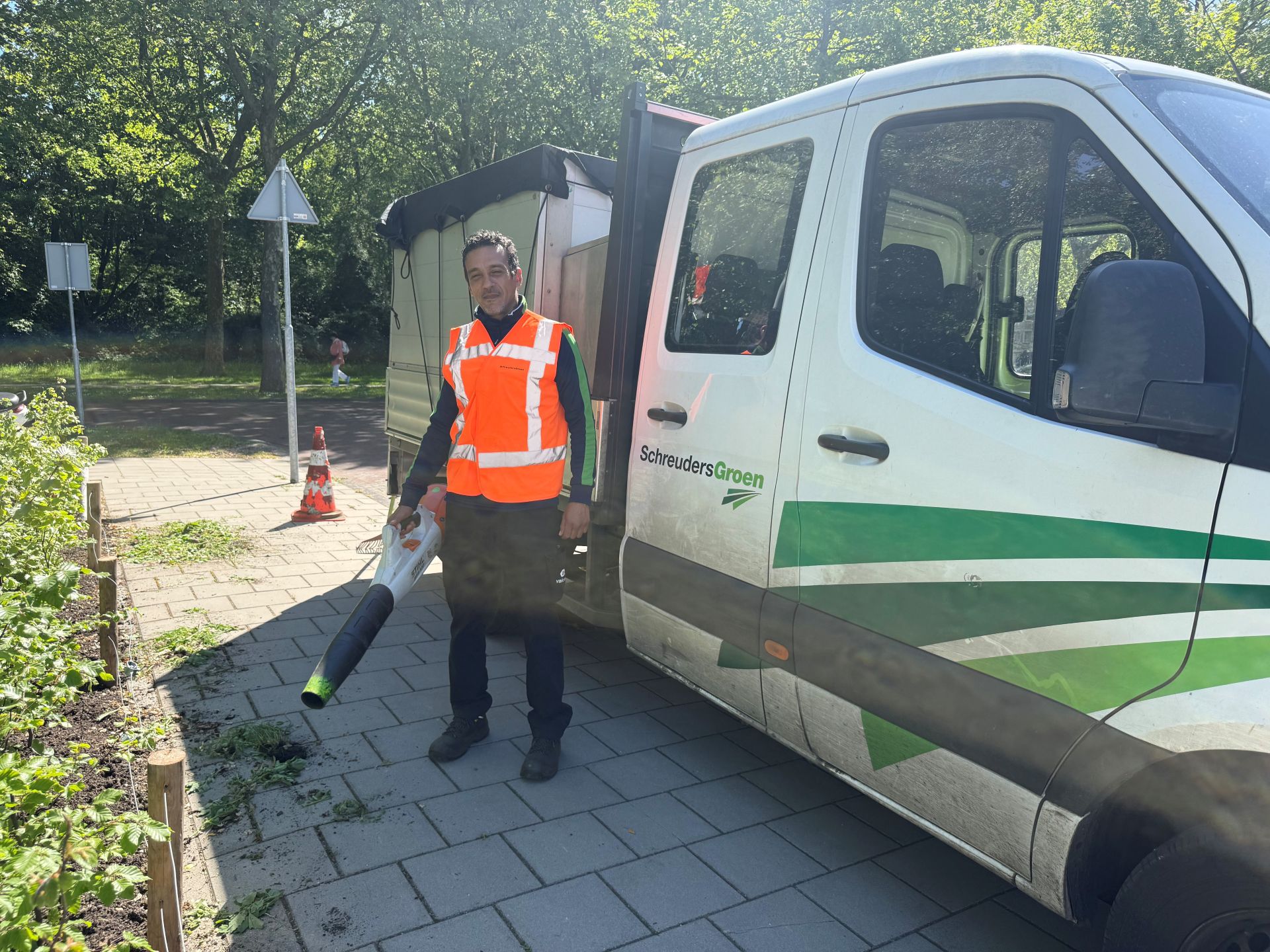 Man in werkkleding met bladblaaser voor een werkbus